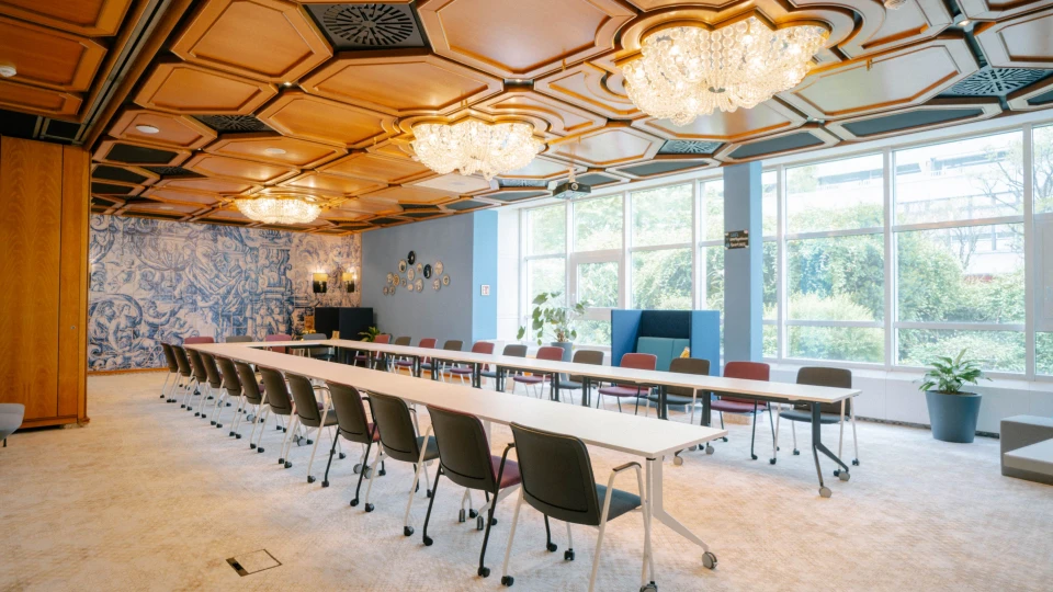 Eleganter Tagungsraum mit Kronleuchtern, Holzdecke und großer Fensterfront für eine helle Atmosphäre