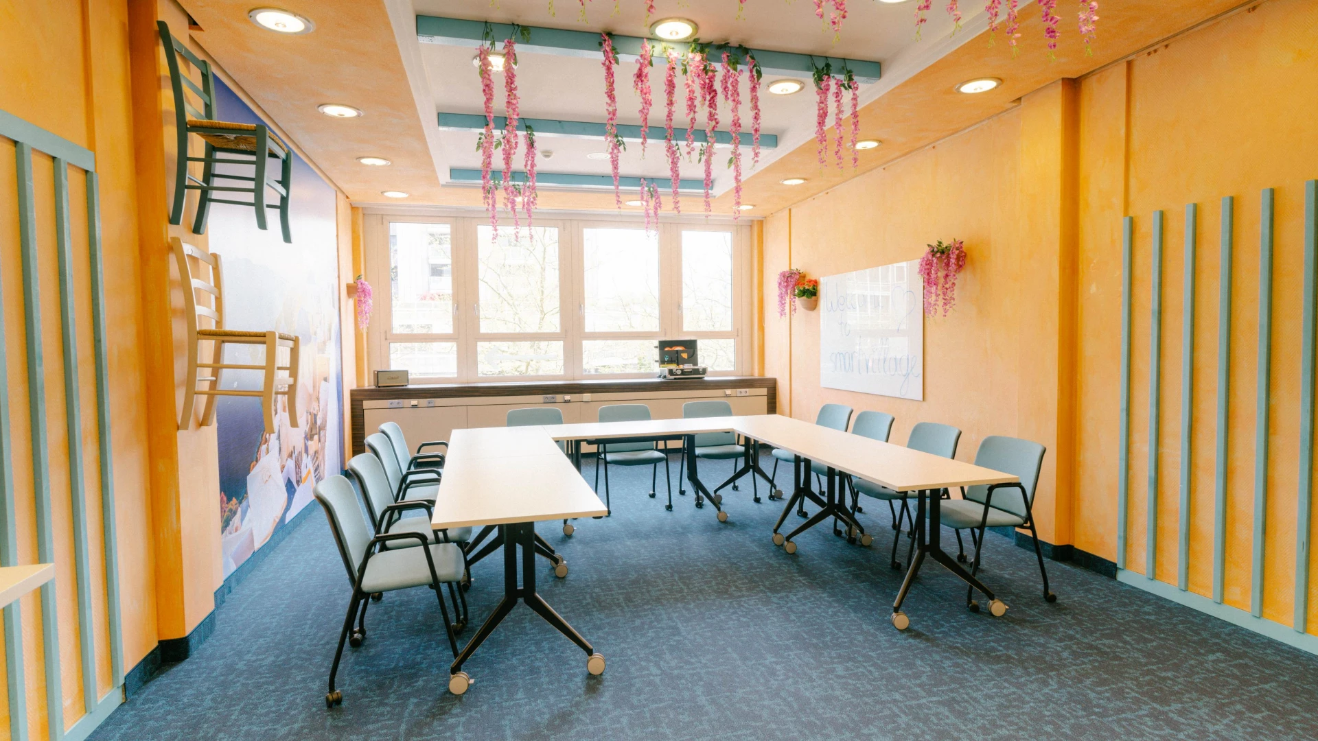 Mediterraner Meetingraum mit pastellfarbenen Wänden, hängenden Blumen und kreativer Dekoration