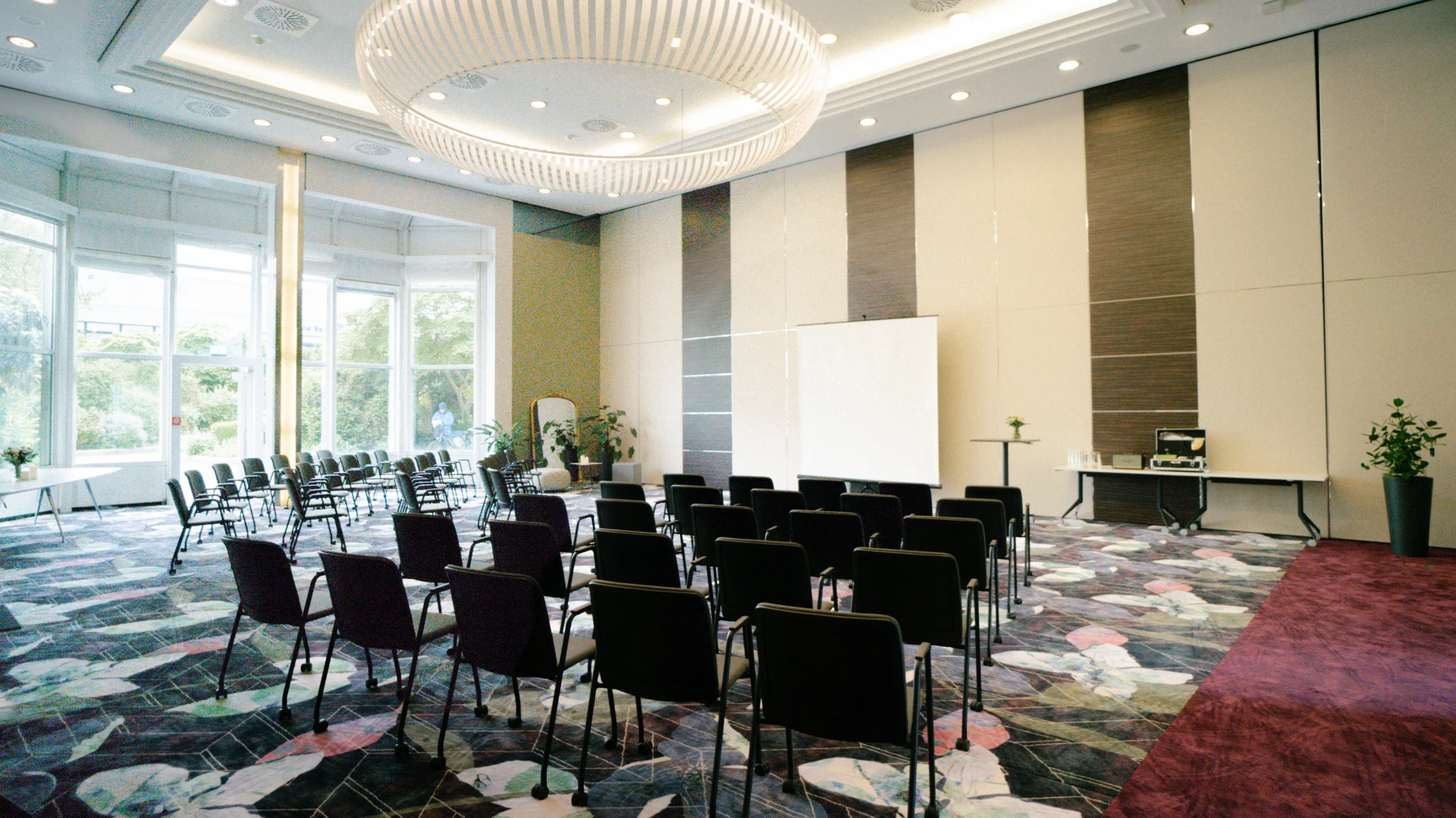 Hochwertiger Eventraum Versailles im Smartvillage Bogenhausen mit Kinobestuhlung, großem Fensterfront und stilvollem Kronleuchter.