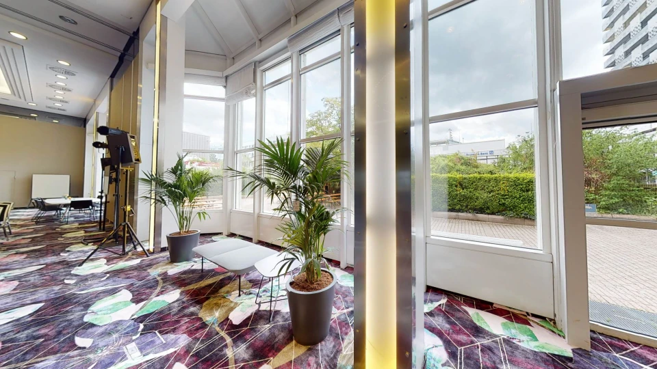 Sitzbereich im lichtdurchfluteten Raum Wien mit hohen Fenstern, Topfpflanzen und gemütlicher Loungemöblierung.