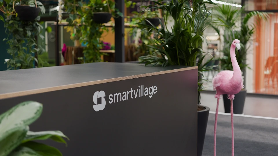Empfangstheke mit smartvillage-Logo und pinkem Flamingo im tropischen Workspace-Design